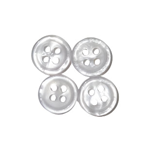 Four white, round, four-hole buttons for Oxford shirts laid out on a surface.