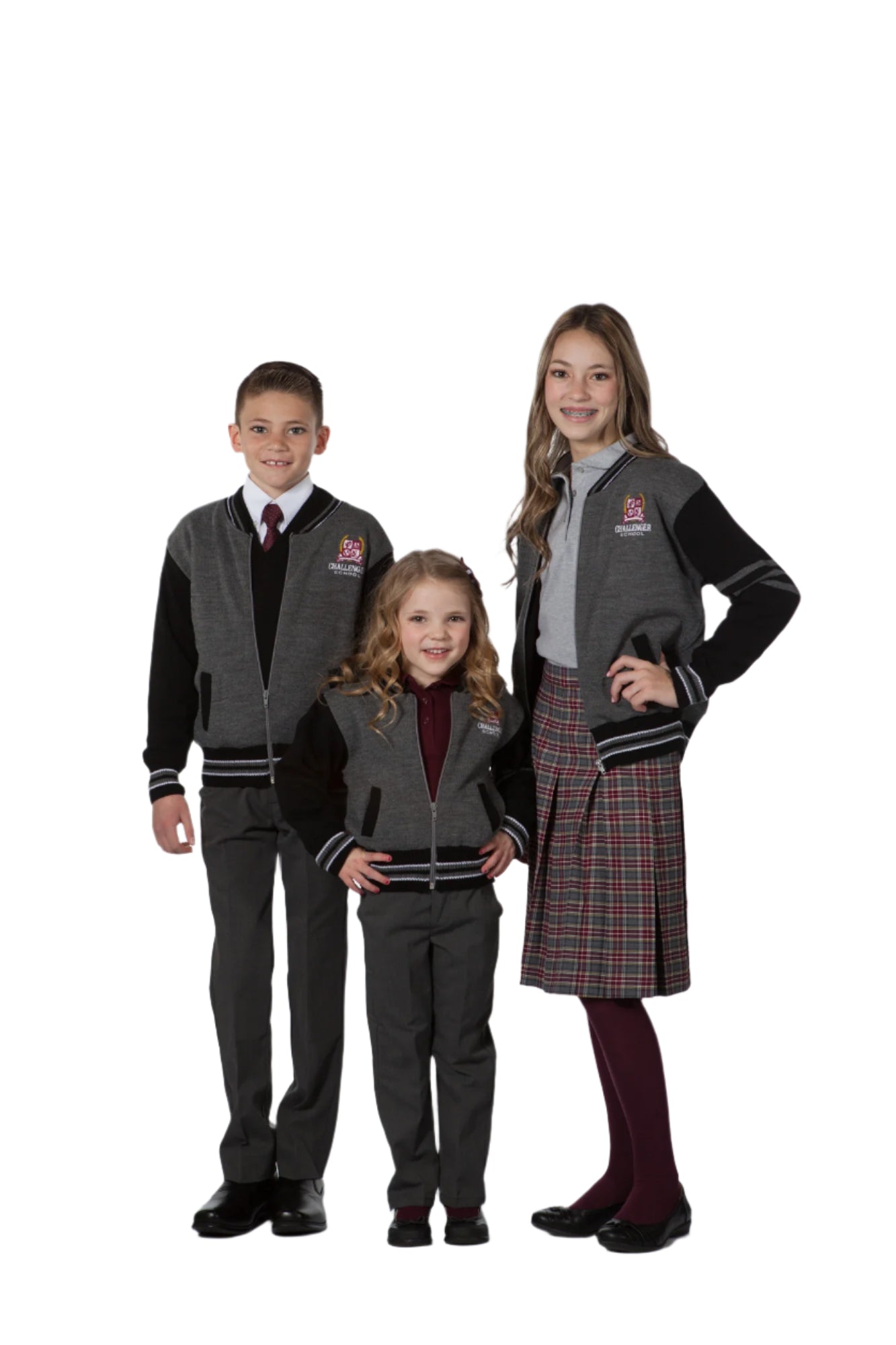 Three children, two wearing varsity jackets in black and grey, standing in a studio setting.